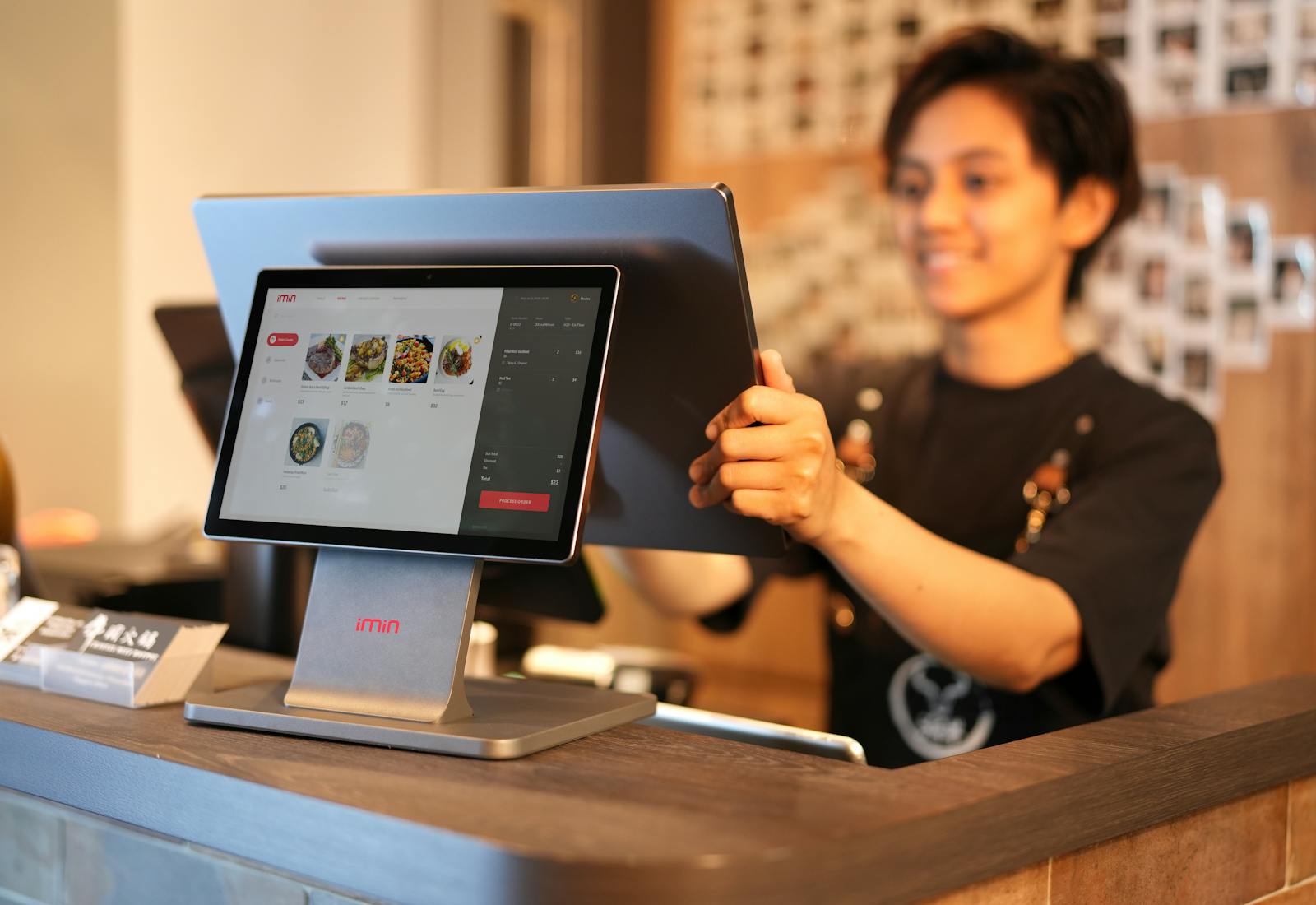 A shopkeeper serving a customer on a touchscreen till.